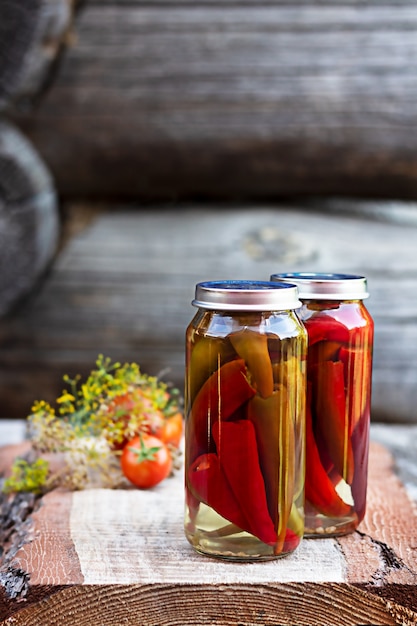 Chilischoten in einem Glas auf einem Holztisch, hausgemachte Gurken