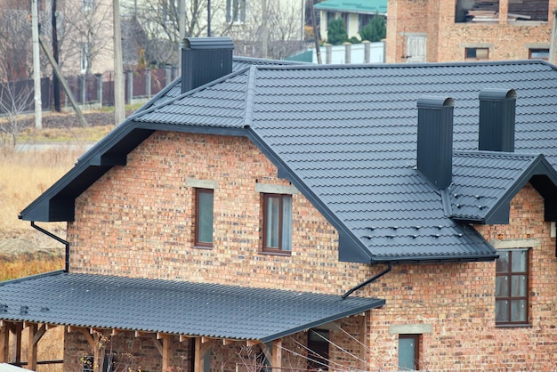 Chimenea en la azotea de la casa cubierta con tejas metálicas en construcción Revestimiento de azulejos del edificio Desarrollo inmobiliario