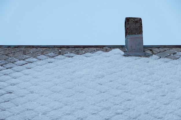 Chimenea de chimenea en casa de techo con cubierta de nieve