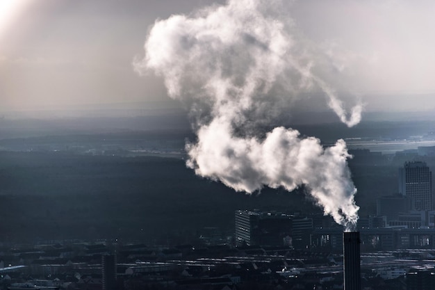 Foto chimenea en la ciudad emitiendo humo contra el cielo