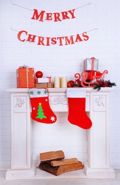 Chimenea con decoración navideña e inscripción "Feliz Navidad" en pared de ladrillo