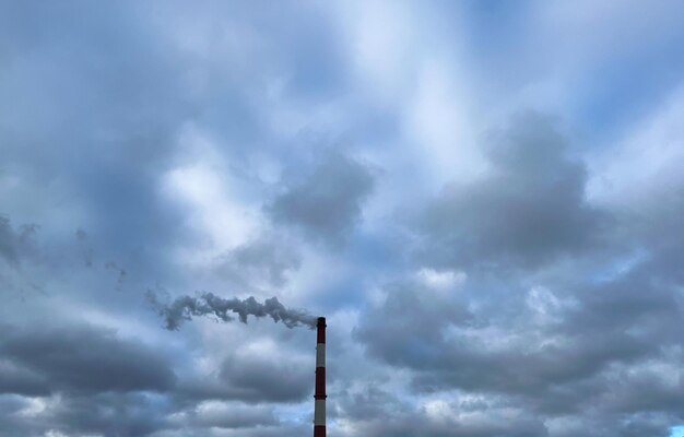 Una chimenea en el fondo de un cielo nublado Emisiones de residuos industriales a la atmósfera