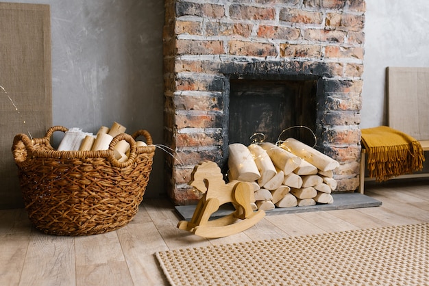 Chimenea de ladrillo rojo con leña y una canasta de leña cerca, caballo de juguete de madera para niños