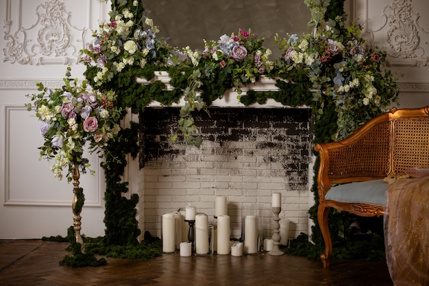 Foto chimenea llena de flores y velas. romántica chimenea de boda decorada con flores de primavera, corona, velas, pared de ladrillo, decoración floral.