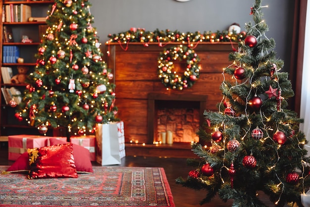 Foto la chimenea de madera está decorada con un árbol de navidad con juguetes rojos al frente y al fondo