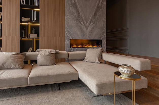 Chimenea de mármol en la sala de estar y librería elegante en un elegante y caro interior de lujosa casa de campo con un diseño moderno con madera y muebles de color gris claro con elementos dorados