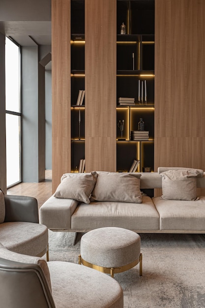 Chimenea de mármol en la sala de estar y librería elegante en un elegante y caro interior de lujosa casa de campo con un diseño moderno con madera y muebles de color gris claro con elementos dorados