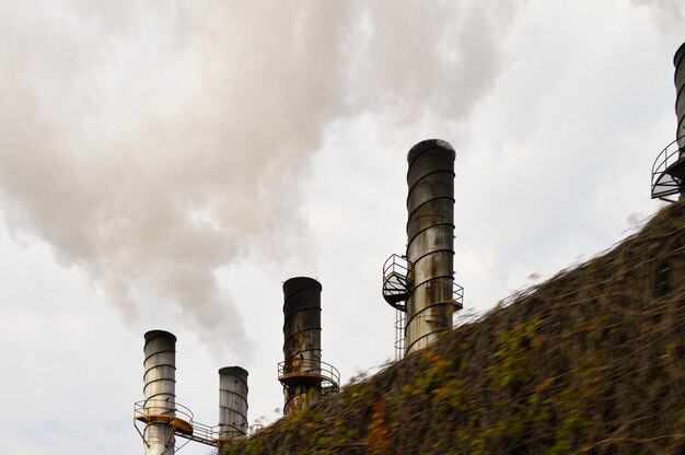 Chimeneas industriales eructando humo contaminante detrás de una valla