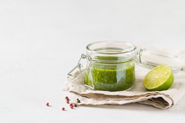 Chimichurri molho verde com ervas frescas e especiarias em jar no fundo branco