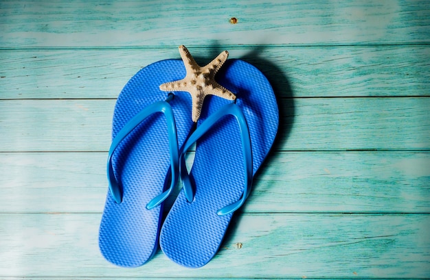 Foto chinelo de praia azul no piso de madeira azul. vista do topo. férias de verâo