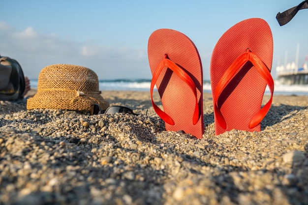 Chinelos de composição de férias de verão e chapéu de palha na areia