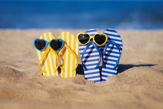 Chinelos e óculos de sol na areia Conceito de férias de verão