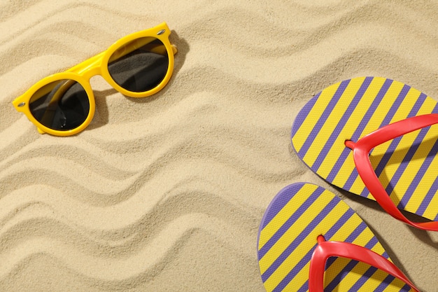 Chinelos e óculos de sol na areia do mar, espaço para texto
