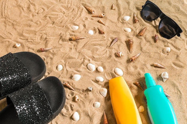 Chinelos pretos e conchas de óculos de sol na areia com lugar para sua visão superior do texto