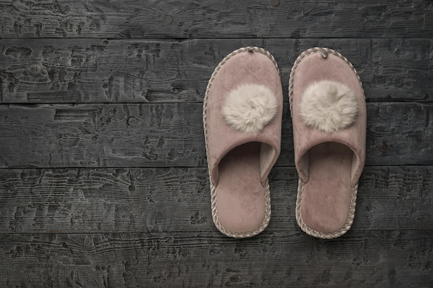 Chinelos quentes em um fundo escuro de madeira O conceito de sapatos para casa