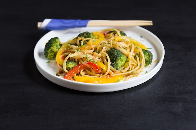 Chinês fritar macarrão udon com legumes na mesa preta, cozido no wok com espaço de cópia