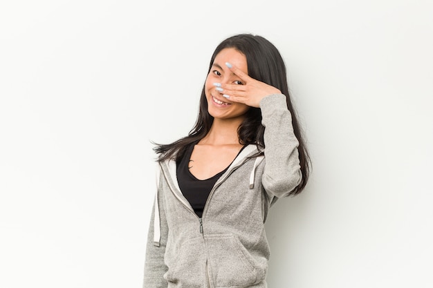 Chinesinblinzeln der jungen Eignung durch Finger, verlegenes Bedeckungsgesicht.