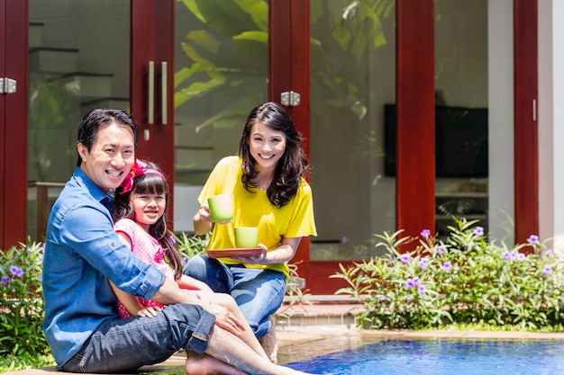 Chinesische familie am pool vor dem haus