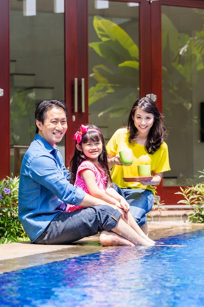 Chinesische Familie am Pool vor dem Haus