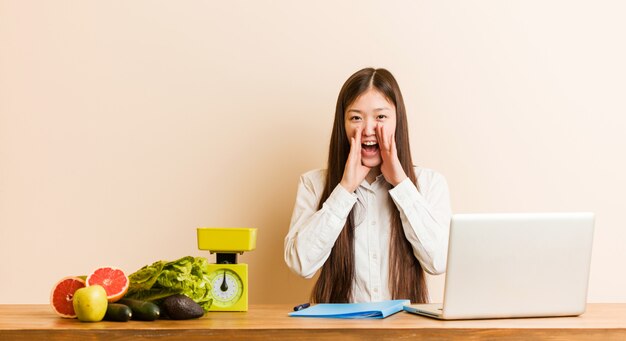 Chinesische Frau des jungen Ernährungswissenschaftlers, die mit ihrem Laptopschreien aufgeregt zur Front arbeitet.