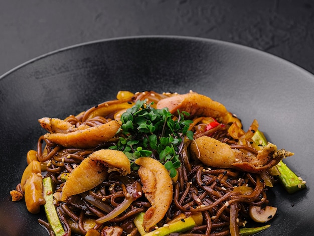 Chinesische gebratene Buchweizenpasta mit Fleisch auf schwarzer Platte