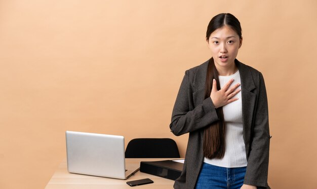 Chinesische Geschäftsfrau an ihrem Arbeitsplatz überrascht und schockiert, während sie richtig aussah