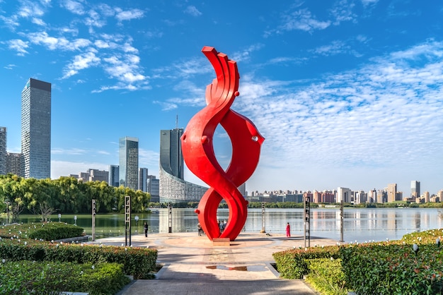 Chinesische moderne Stadt mit roter abstrakter Skulptur durch den Fluss