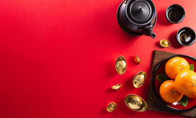 Chinesische Neujahrsdekorationen aus rotem Paket, Orangen- und Goldbarren oder goldenem Klumpen auf rotem Hintergrund. Die chinesischen Schriftzeichen FU in dem Artikel beziehen sich auf Glück, Glück, Reichtum, Geldfluss.