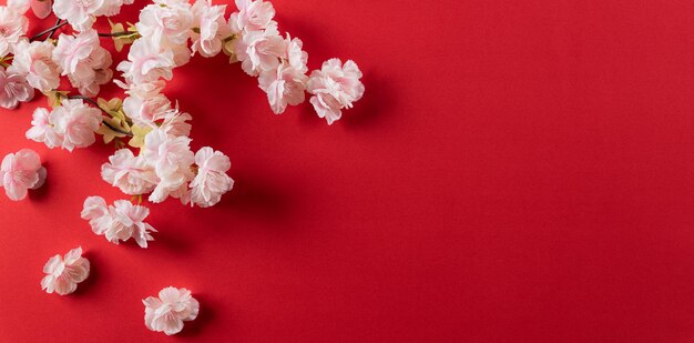 Chinesische Neujahrsfestdekorationen aus Pflaumenblüten auf rotem Grund. Flache Lage, Draufsicht mit Kopienraum.