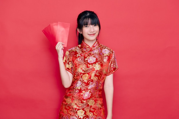 Chinesische Neujahrsjunge Frau, die roten cheongsam hält Umschlag hält
