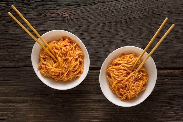 chinesische Nudel. mit Stäbchen und chinesischen Nudeln in süß-saurer Sauce in einer Schüssel