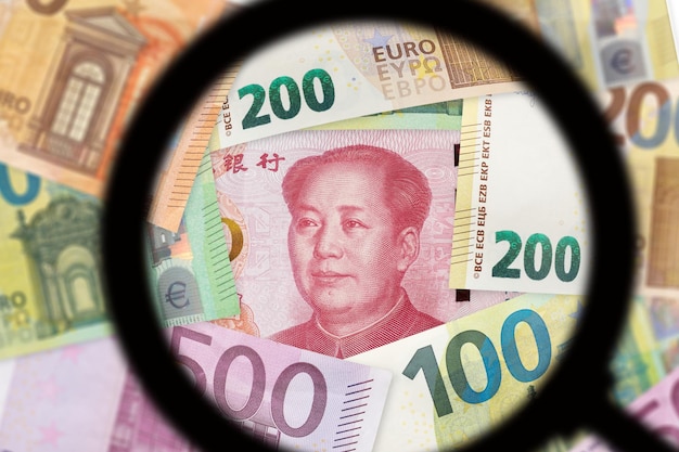 Chinesische Yuan- und Euro-Banknoten Handelskrieg zwischen der EU und China Durch eine Lupe zu sehen