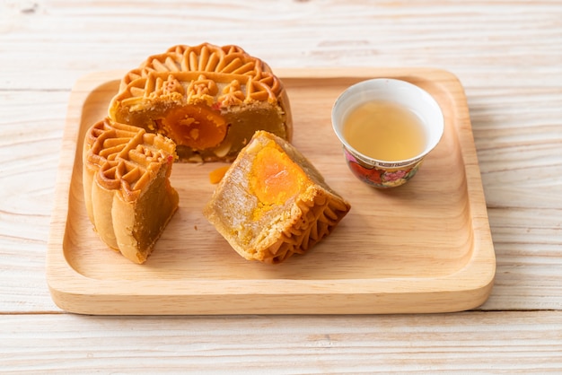 Chinesischer Mondkuchen Durian und Eigelbgeschmack mit Tee auf Holzteller