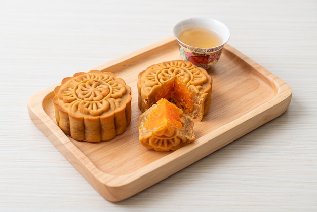 Chinesischer Mondkuchen Durian und Eigelbgeschmack mit Tee auf Holzteller