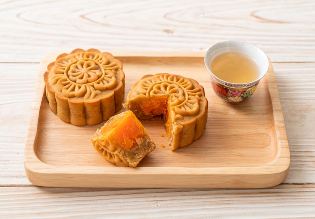 Chinesischer Mondkuchen Durian und Eigelbgeschmack mit Tee auf Holzteller