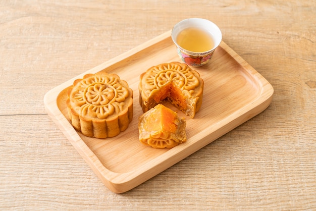 Chinesischer Mondkuchen Durian und Eigelbgeschmack mit Tee auf Holzteller