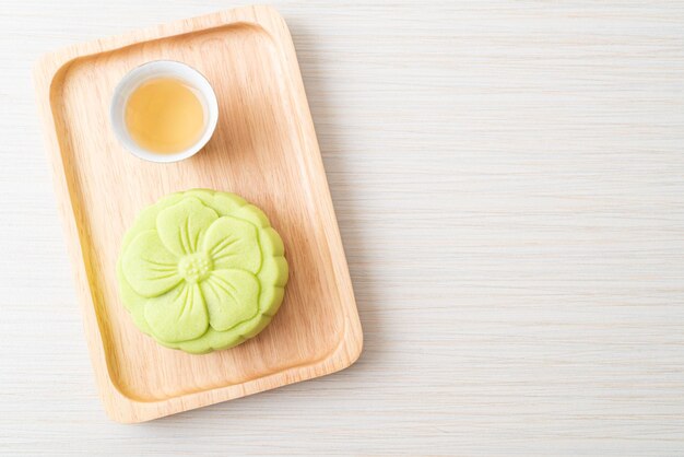 Chinesischer Mondkuchen-Grüntee-Geschmack mit Tee auf Holzplatte