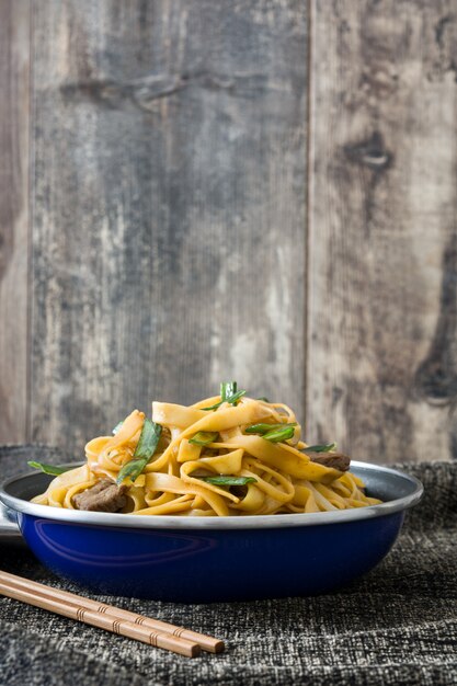 Foto chinesisches essen rindfleisch chow mein in bratpfanne auf holztisch auf holztisch