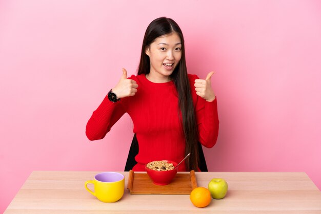 Chinesisches Mädchen, das an einem Tisch sitzt und frühstückt