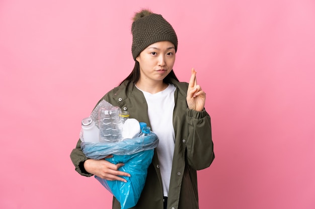 Chinesisches Mädchen, das eine Tasche voller Plastikflaschen hält, um zu recyceln