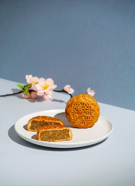 Chinesisches traditionelles Gebäck Mondkuchen, Mondkuchen, das chinesische Schriftzeichen auf der Kuchenübersetzung in Englisch ist "Lotuspaste", Mid-Autumn Festival, grelles Sonnenlicht, blauer Hintergrund, modernes Stillleben