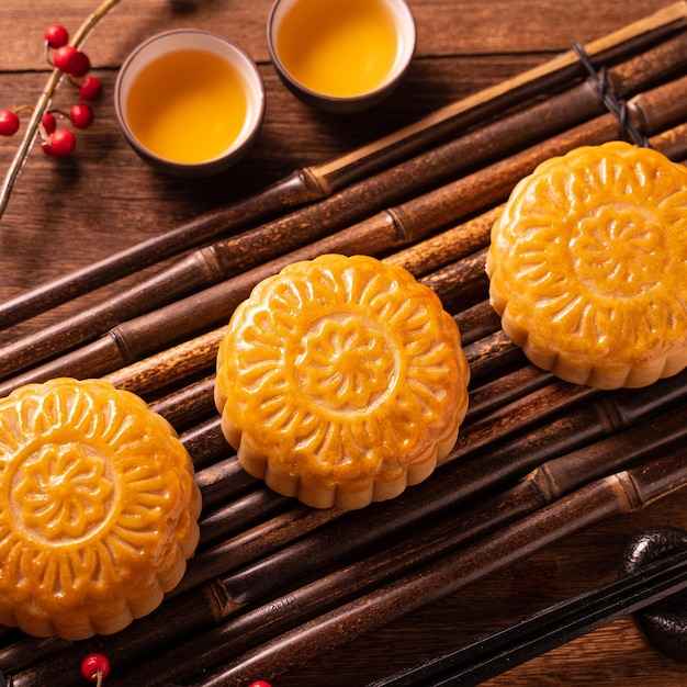 Chinesisches traditionelles Gebäck Mondkuchen Mondkuchen mit Teetassen auf Bambusservierwarntablett auf Holzhintergrund für MidAutumn Festival aus nächster Nähe