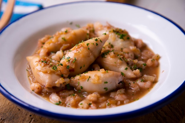 Chipirones Calamares guisados con verduras, gambas y patatas. Receta tradicional de tapa española.