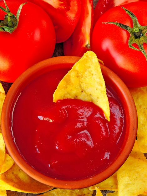 Foto chips amarelos triangulares e molho vermelho com tomate