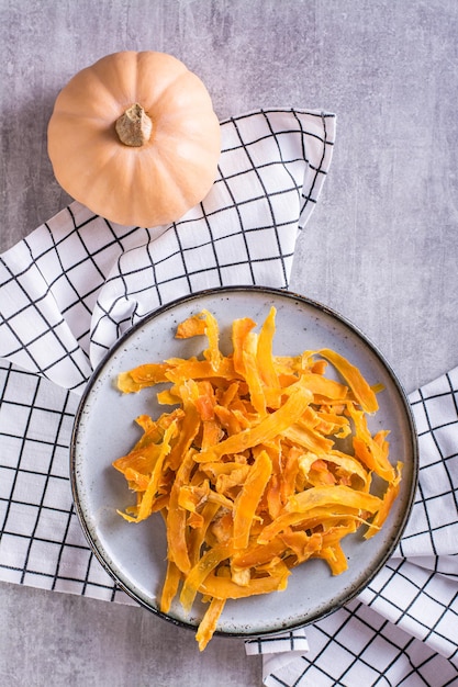 Chips de calabaza horneados orgánicos caseros en un plato sobre la mesa y vista vertical