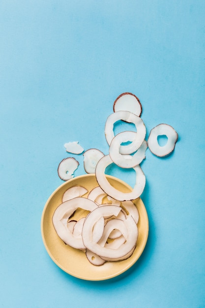 Chips de coco en un plato amarillo sobre azul