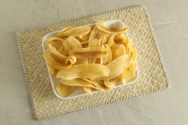 Foto chips de banana crocantes, banana fatiada frita ou assada, servida em prato branco