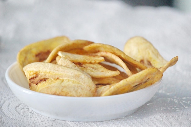 Chips de banana em uma tigela branca sobre um fundo branco pronto para venda