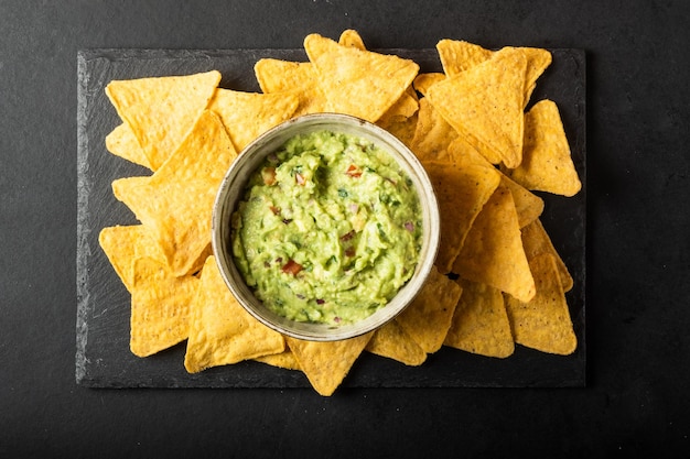 Chips de nachos mexicanos e tigela com molho de guacomole fresco caseiro feito de abacate e limão