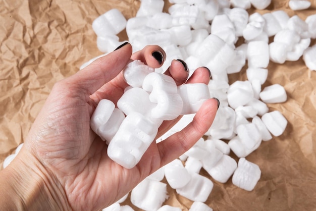 Chips de embalaje blanco cacahuete de espuma de poliestireno en mano de mujer